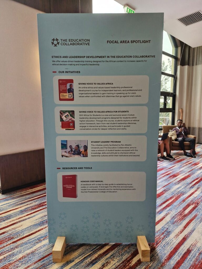 A standing display board highlights "Ethics and Leadership Development in the Education Collaborative," featuring key initiatives, resources, and tools. The board stands on a carpeted floor in a well-lit room.